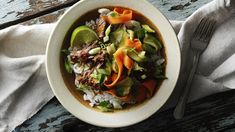 a bowl filled with rice, meat and veggies on top of a wooden table