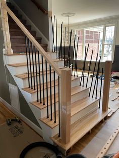 a wooden staircase with black railings and wood handrails in a house under construction