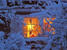 the window is covered in snow and lit up at night, with candles on the windowsill