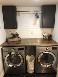 a washer and dryer in a small room with dark wood cabinets on the wall