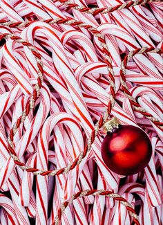 a red ornament sitting on top of a pile of white candy canes