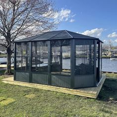 a gazebo sitting on top of a lush green field next to a body of water