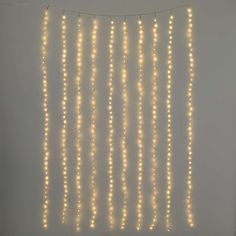 string lights hanging from the ceiling in front of a wall with white lights on it