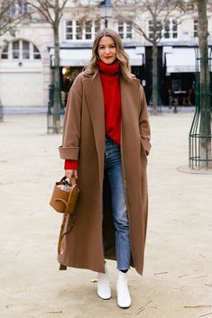 a woman in a red turtle neck sweater and brown coat