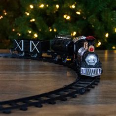 a toy train is on the tracks in front of a christmas tree