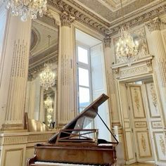 a grand piano sitting in front of a chandelier