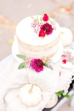 a three tiered cake with flowers and leaves on it sitting on top of towels