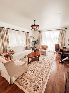 a living room filled with furniture and a rug on top of a hard wood floor