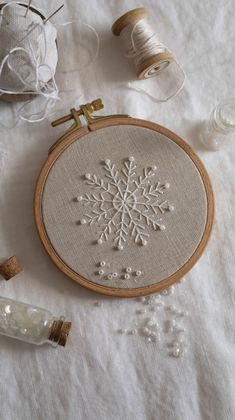 an embroidered snowflake on a table next to some thread and spools