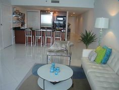 a living room filled with furniture and a kitchen in the backgroung area