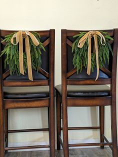 two wooden chairs with wreaths tied to the back and seat covers on each side