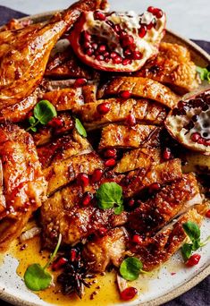 a white plate topped with meat covered in pomegranate and garnish