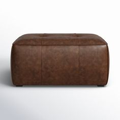 a brown leather ottoman sitting on top of a white floor