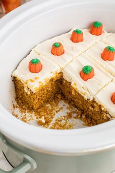 a carrot cake with white frosting and orange pumpkins on top, in a crock pot