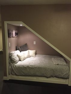 a bed that is in the corner of a room with pillows on top of it