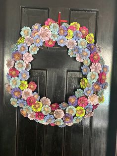 a wreath with flowers hanging on the front door