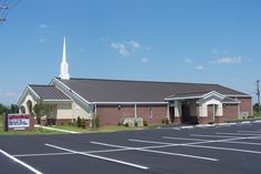 an empty parking lot in front of a church with a steeple on the roof