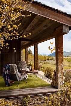 a covered porch with a chair and table in the foreground, mountains in the background