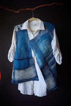 a blue and white vest hanging on a clothes line next to an orange dress shirt