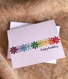 two cards with colorful flowers on them sitting next to each other in front of a burlap background