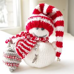 a knitted snowman ornament with a red and white striped hat on