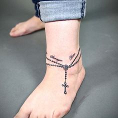 a woman's foot with a rosary and cross tattoo on the side of her ankle