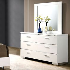 a white dresser with two vases on top of it and a mirror above it