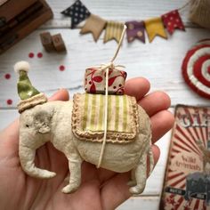 a hand holding a small toy elephant with a birthday hat on it's head