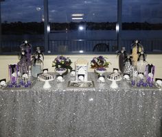 a table set up with silver sequins and purple decorations for a halloween party