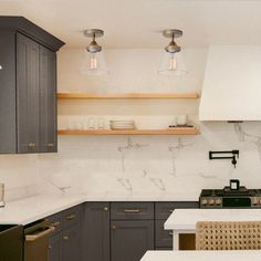 a kitchen with gray cabinets and white counter tops is pictured in this image, there are two pendant lights above the stove