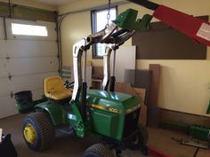 a green tractor parked inside of a garage