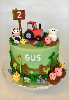 a green cake with farm animals on it and a sign that says gus in the middle