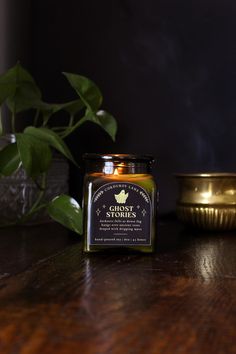 a candle sitting on top of a wooden table next to a potted plant