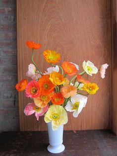 a white vase filled with lots of colorful flowers