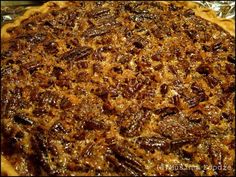 a pie with pecans on it sitting on top of tin foil covered baking pan