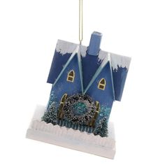 a blue house ornament hanging from a gold chain on a white background with snow