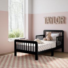 a teddy bear sitting on top of a bed in a room with pink and white walls