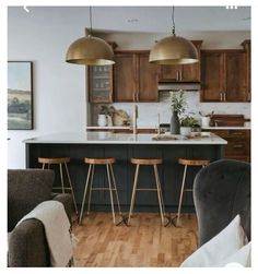 an open kitchen with bar stools next to the counter top and wooden flooring