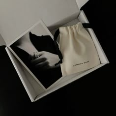 an open white box containing a ring and a black and white photo with a bow on it