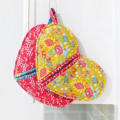 two hats hanging on the side of a white door, one has a red and yellow flowered design