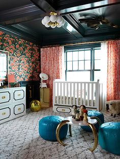 a living room filled with furniture and walls covered in colorful wallpaper, along with a baby's crib