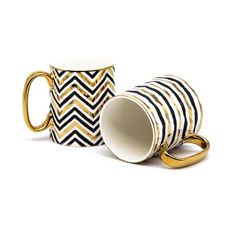 two black and white coffee mugs with gold handles, one has a chevron pattern on it