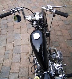 a black motorcycle parked on top of a brick road