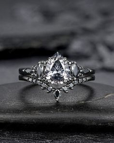 a white diamond ring sitting on top of a black stone slab with other stones in the background