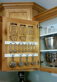 a wooden cabinet with measuring spoons and measuring cups on the bottom, labeled kitchen utensils