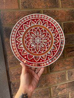 a hand holding up a red and white decorative plate