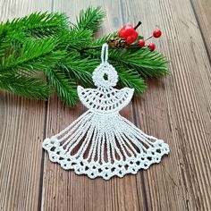 a crocheted christmas ornament hanging from a pine branch on a wooden table