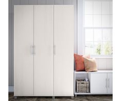 a white wardrobe with two doors and some pillows on the floor next to it in front of a window