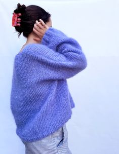 a woman in a blue sweater is covering her face