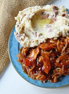 a blue plate topped with mashed potatoes and pulled pork covered in gravy